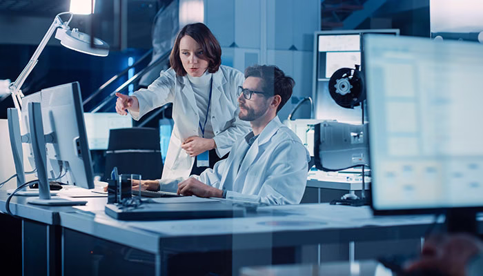 2 persons in a lab discussing in front of computer screens